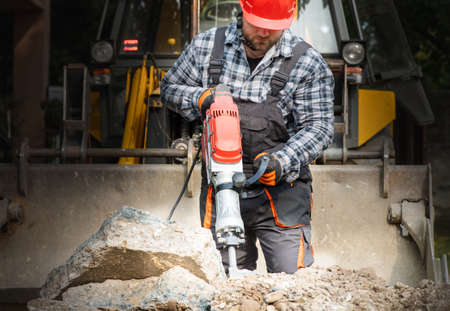 A laborer as he uses a jackhammer to break up a reinforced concrete pavementの写真素材