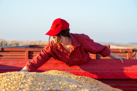 Young farmer girl in the corn field. Agricultural machinery in backgroundの写真素材