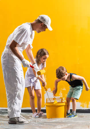 Family painting their room together in yellow.の写真素材