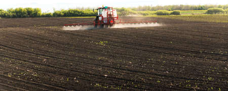 Tractor spraying pesticides on field  with sprayer
