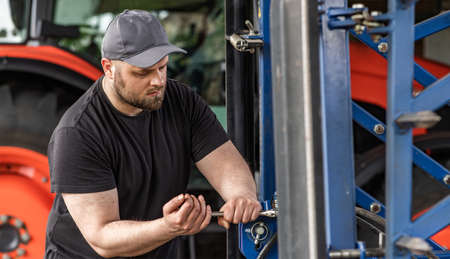 The farmer repairs agricultural machines in field