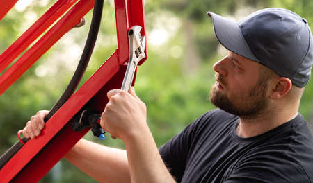 The farmer repairs agricultural machines in field