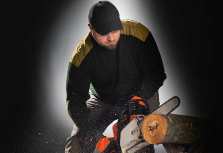 worker cuts firewood with a chainsaw