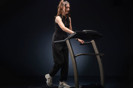 A beautiful athletic girl runs on a treadmill in a fitness club. Concept: cardio training, weight...