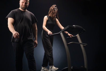 Fitness instructor helps young women on elliptical trainer.
