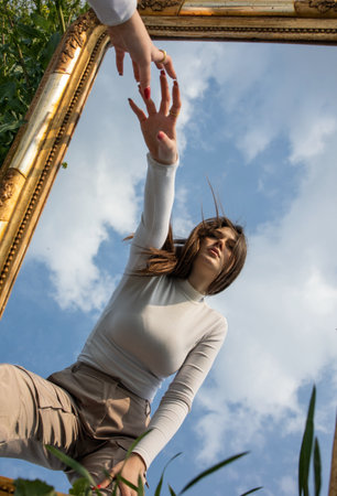 Beautiful young woman with a rectangular mirror on the field of young wheat
