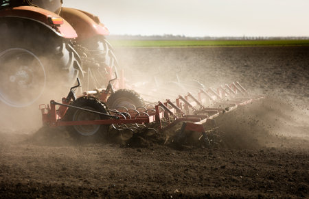 A farmer in a tractor prepares his field as the sun begins to set.