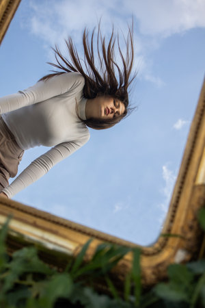 Beautiful young woman with a rectangular mirror on the field of young wheatの写真素材