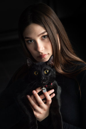 beautiful young woman in black sweater with black cat,の写真素材