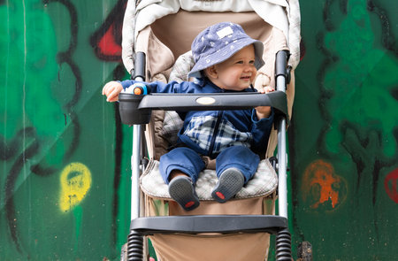 Cute little beautiful baby boy sitting in the strollerの写真素材