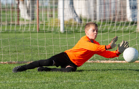 Young Boy Goalkeeper Saving A Football In A Game Of Soccer.の写真素材