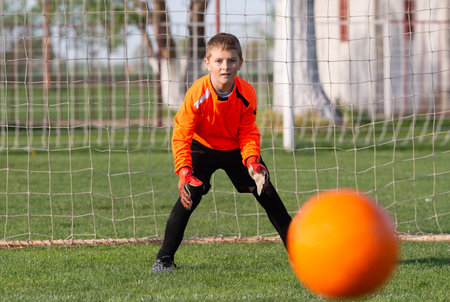 Young Boy Goalkeeper Saving A Football In A Game Of Soccer.の写真素材