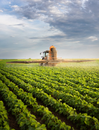 Tractor spraying pesticides on soy field  with sprayer at spring