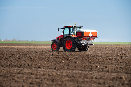 Tractor spreading artificial fertilizers  in field