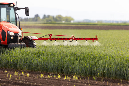 Tractor spraying pesticides over a green fieldの写真素材