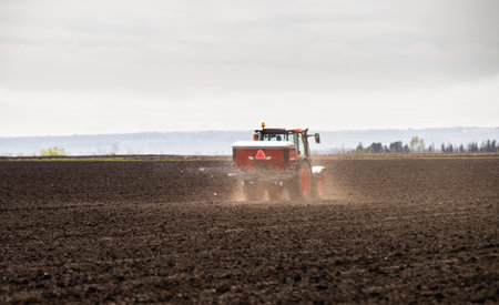 Tractor spreading artificial fertilizers  in field