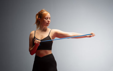 Woman in black sports clothes exercising with resistance band in studio. Resistance Band Workout For...