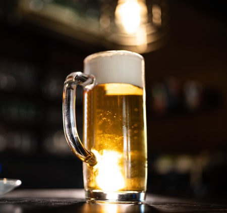 a beer mug is standing on a sled. Golden beer with bubbles and foamの写真素材