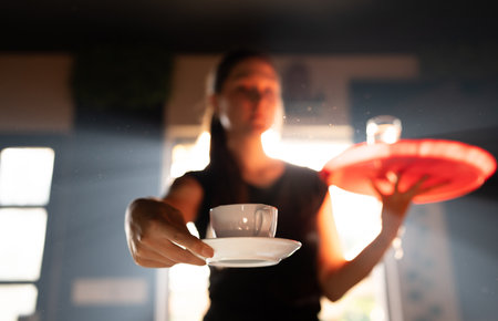 Portrait of young female waitress serving coffee at the cafeの写真素材