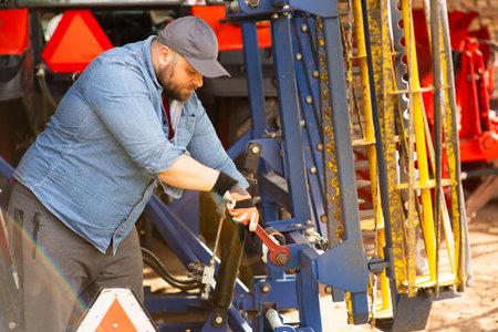 The farmer repairs agricultural machines in fieldの写真素材