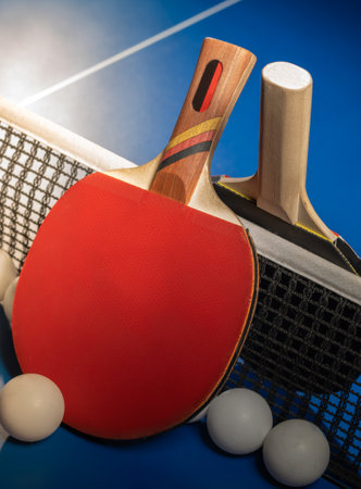Two table tennis rackets and balls on a blue table with net.の写真素材