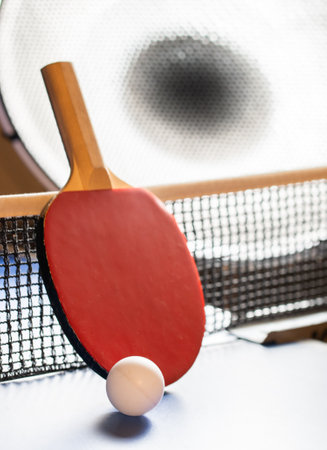 Two table tennis rackets and balls on a blue table with net.