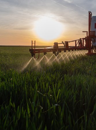 Tractor spraying pesticides over a green fieldの写真素材