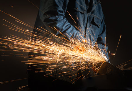 Workman using power tool with hot metal sparks