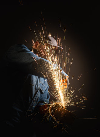 Workman using power tool with hot metal sparksの写真素材