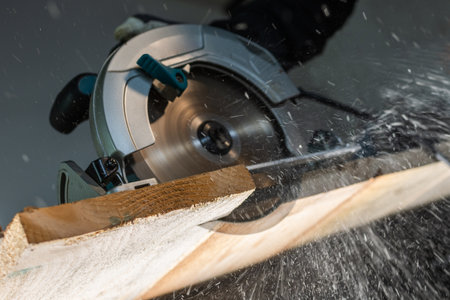 Close-up of a carpenter using a circular saw to cut a large board of woodの写真素材