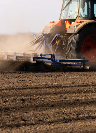 Tractor plowing farm preparing soil for new crop plantation during the evening.