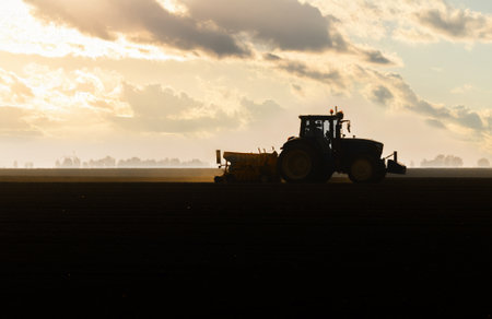 Farmer with tractor seeding - sowing crops at agricultural field. Plants, wheat.の写真素材