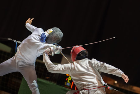 Fight at a fencing competition. Two fencing athletes fight on professional sports arena