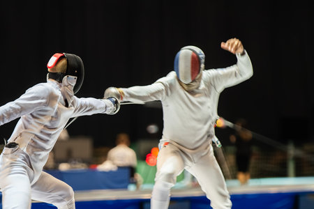 Fight at a fencing competition. Two fencing athletes fight on professional sports arena