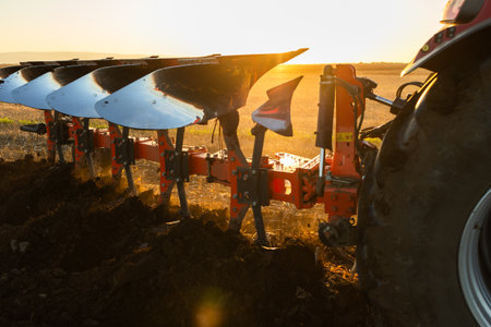 Tractor on the field during sunset. Tractor plows the field in the evening at sunsetの写真素材
