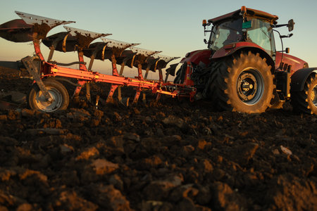 Tractor on the field during sunset. Tractor plows the field in the evening at sunsetの写真素材
