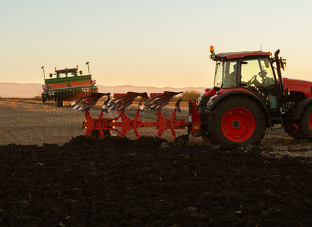 Tractor on the field during sunset. Tractor plows the field in the evening at sunsetの写真素材