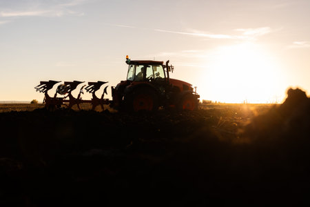 Tractor on the field during sunset. Tractor plows the field in the evening at sunset