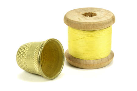 Old brass thimble and the coil of threads for sewing on a white backgroundの写真素材