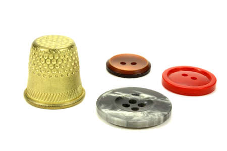 Old brass thimble and color buttons for sewing on a white backgroundの写真素材