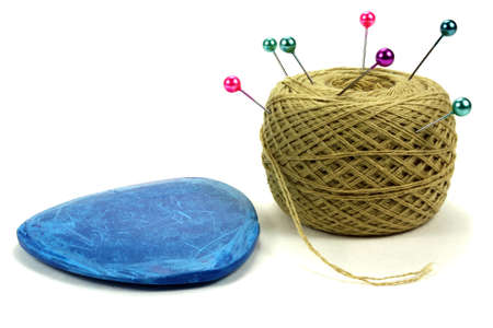 Color pins for sewing with the coil of threads and blue chalk on a white background