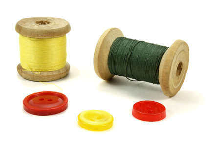 Wooden coil with threads and color buttons on a white background