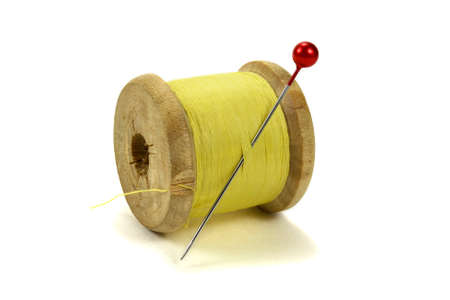 Wooden coil with threads and pin for sewing on a white background
