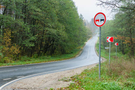 The asphalt forest road in rainy autumn day