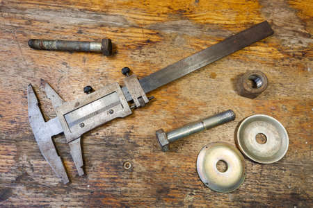 Caliper, bolt and nut on a table in a workshopの写真素材