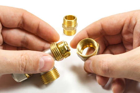 Plumbing fitting in the master's hands on a white background
