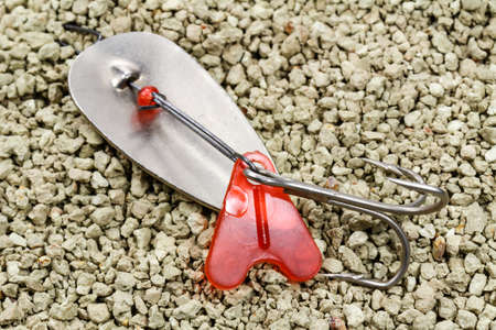 Old fishing metal spinner on a rocky soil backgroundの写真素材