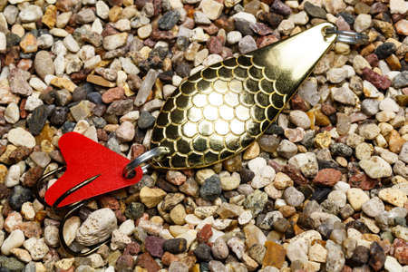 Golden metal fishing bait for a spinning on the stony ground