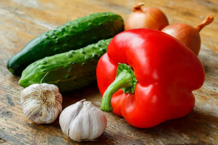 Garlic, sweet pepper, cucumbers and onions on a old wooden tableの写真素材