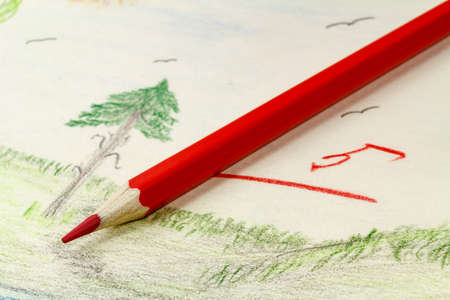 Red pencil on the background of children's drawingの写真素材